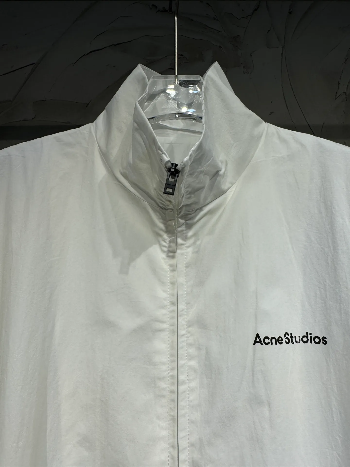 ACNE STUDIOS distressed letter printed loose stand-up collar sports jacket. Double-layer fabric inside and outside. The outer layer is made of 100% polyester woven sportswear fabric. The inner mesh is punched and Breathable lining. The version is short, large bust stand-up collar sports version. The letters are printed on the back. Single-color screen printing glue printing. It has an old leakage effect. Fully automatic elliptical machine printing glue printing. The printing is evenly stressed and complete without burrs. The upper part of the whole garment is hand-sprayed with horse-drawn distressed paint. Each piece is hand-sprayed individually to create an distressed look. Size: S M L Color: distressed black, distressed white, distressed Navy Blue